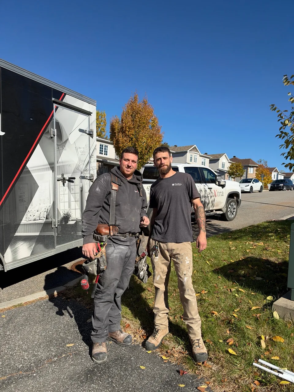 Deux installateurs devant une remorque et une camionnette FenXtra, à l’extérieur.