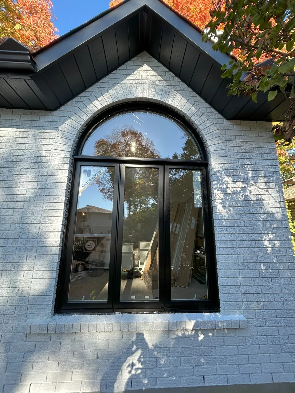Black-framed window with an arched top in a light brick façade.