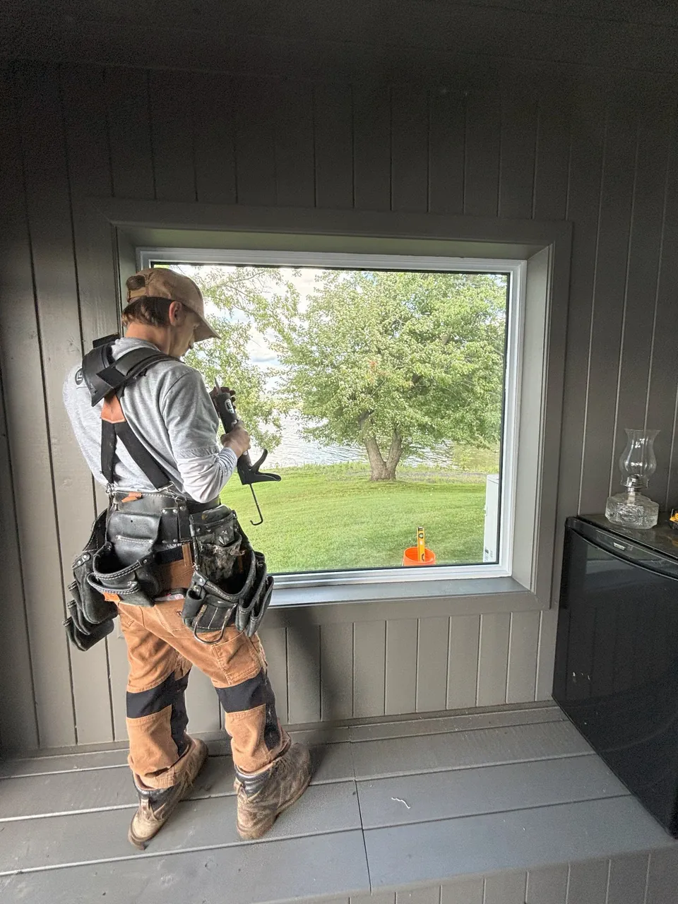 An installer working beside a large white window indoors.