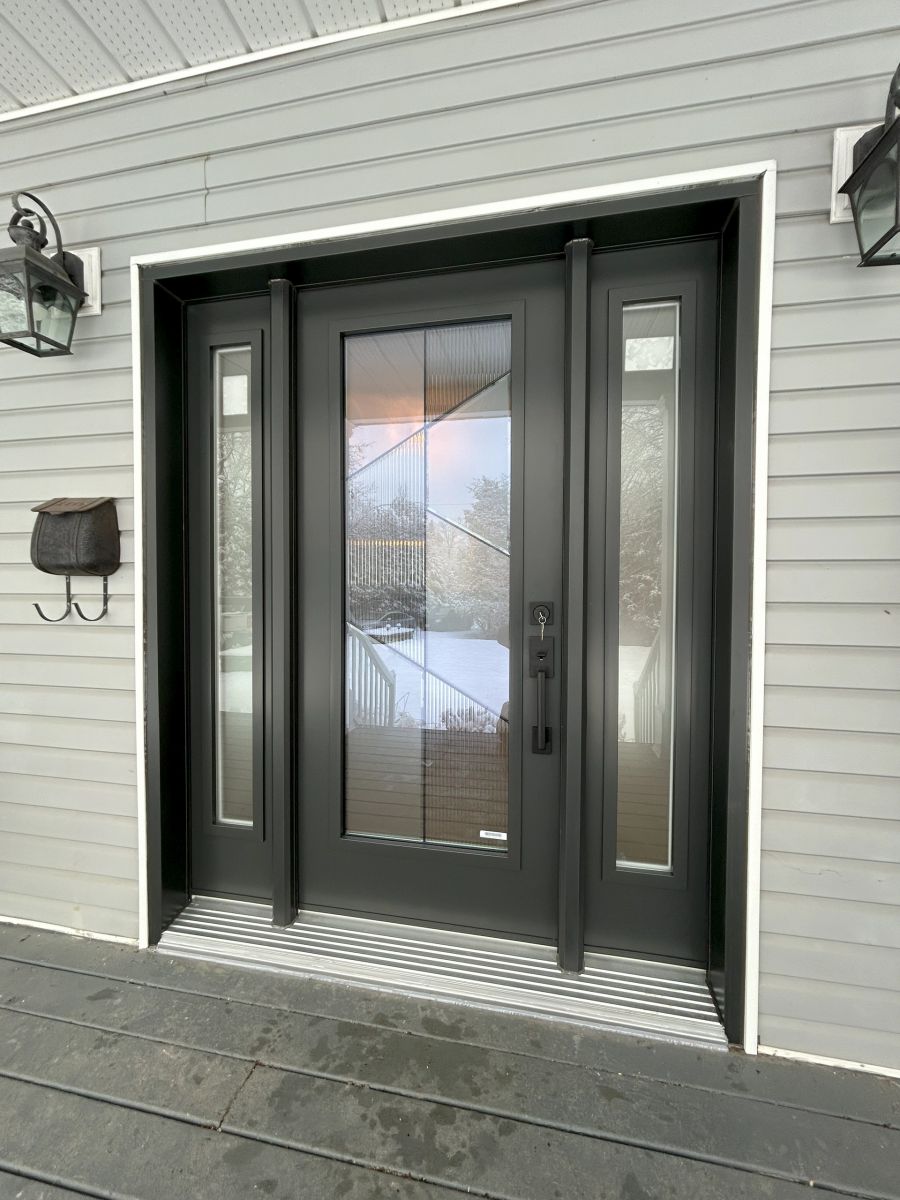 Dark entrance door with decorative glass, two sidelights and light exterior siding.