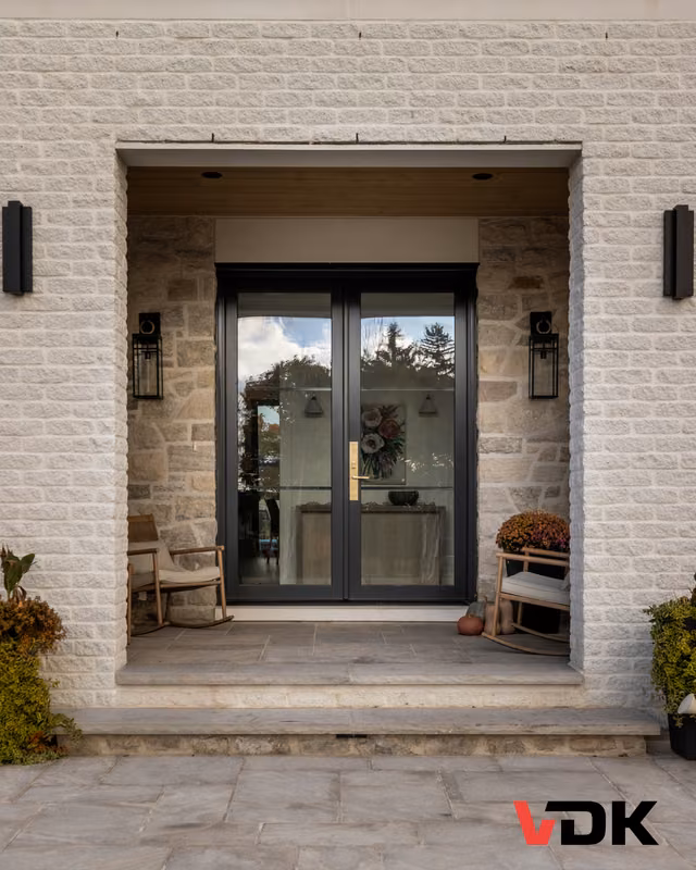 Référence VDK : entrée double vitrée dans une façade de pierre et de brique claires; logo VDK visible.