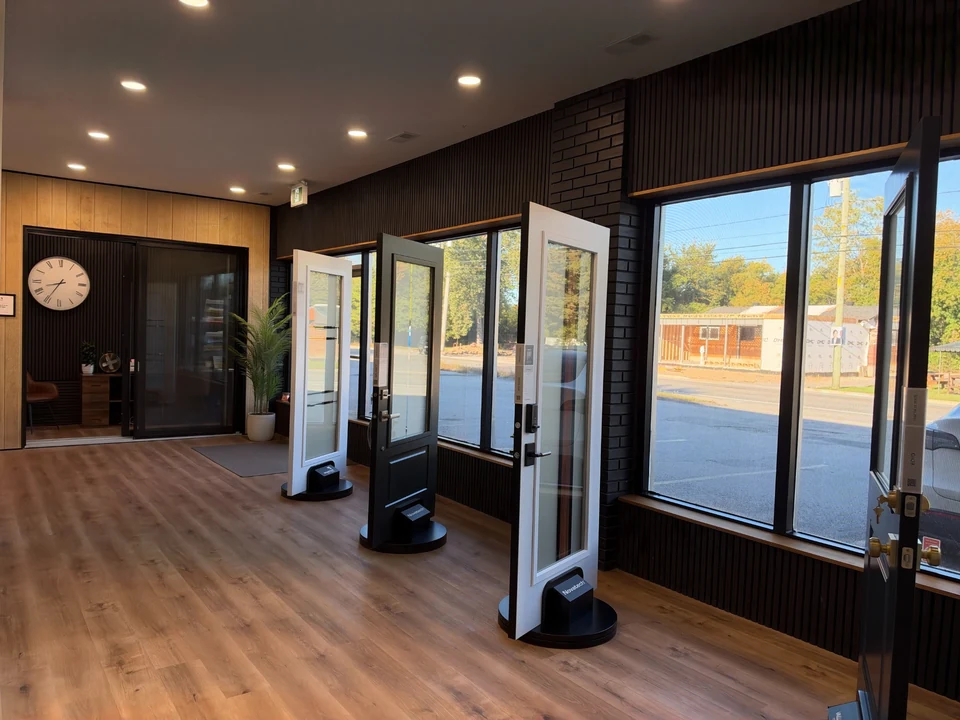 FenXtra showroom with glazed doors on display stands, a wood floor and large street-facing windows.