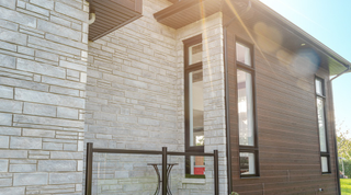 Manufacturer photograph: black windows with transoms in a stone and wood façade.